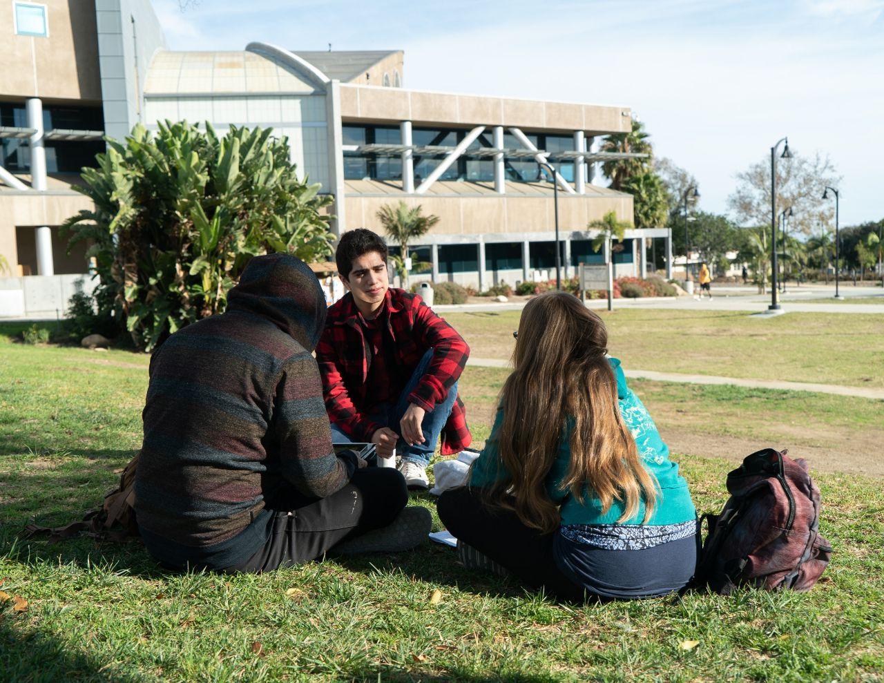 三个学生坐在草坪上